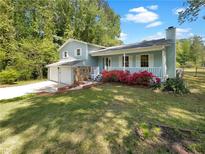 Charming home with a well-maintained lawn, colorful flowers, and a stone facade on a two-car garage at 4357 Treeline Way, Douglasville, GA 30135