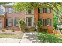 Beautiful brick home featuring a decorative wood front door, manicured landscaping, and stone steps at 2355 Twelvestones Dr, Roswell, GA 30076