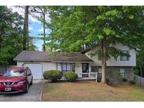 Charming two-story home with a well-maintained lawn, mature trees, and a visible garage at 6193 Charring Cross Ct, Lithonia, GA 30058