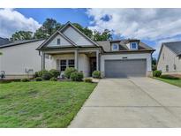 Charming single-Gathering home featuring a two-car garage, and a welcoming front porch with manicured landscaping at 5650 Bergeson Ways, Cumming, GA 30028
