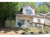 Charming two-story home with light siding, shutters, tidy landscaping, and a newly stained, wooden fence at 70 Gardenia Nw Dr, Atlanta, GA 30314