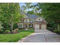 Traditional two-story home with a well-manicured lawn, mature trees, and a two-car garage at 6795 Preston Glen Dr, Alpharetta, GA 30005
