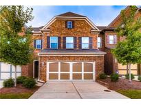 Charming brick townhome featuring a two-car garage and manicured landscaping, offering a welcoming curb appeal at 4150 Cedar Bridge Walk, Suwanee, GA 30024