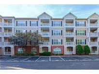 Tan condo building with balconies, brick accents, reserved parking and a colorful tree in front at 4333 Dunwoody Park # 2107, Atlanta, GA 30338