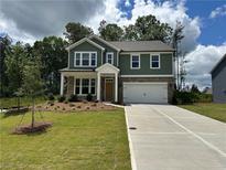Inviting two-story home with a green exterior, stone accents, manicured lawn, and an attached two-car garage at 5377 Heron Bay Blvd, Locust Grove, GA 30248