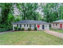 Charming single-story home with a well-maintained lawn, a red door, and complemented by lush green trees at 2529 Habersham Dr, Decatur, GA 30032