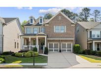 Beautiful two-story brick home featuring a welcoming front porch, manicured landscaping, and a two-car garage at 127 Marlow Dr, Woodstock, GA 30188