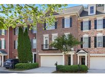 Charming brick townhome featuring black shutters, a two-car garage, and manicured landscaping at 478 Vinings Estates Se Dr # B02, Smyrna, GA 30126