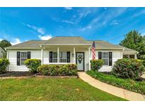 Charming single-story home with landscaped front yard and cozy covered porch, complete with an American flag at 472 Linda Ln, Powder Springs, GA 30127