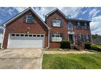 Traditional two-story brick home with an attached two-car garage and well-manicured landscaping at 5704 Winchester Pl, Lithonia, GA 30038