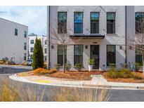 Charming townhome featuring a painted brick facade, black framed windows and tasteful landscaping at 472 Burton Dr, Alpharetta, GA 30009