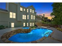 Backyard view of a pool with a stone waterfall feature and a spa, set against a serene twilight sky at 120 Generals Pl, Canton, GA 30114