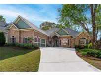 Charming brick home with lush landscaping, long driveway, and a welcoming facade under a bright blue sky at 2111 Democracy Dr, Buford, GA 30519