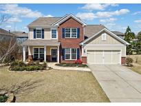 Charming two-story home featuring a red brick facade, manicured landscaping, and an attached two-car garage at 441 Spring View Dr, Woodstock, GA 30188