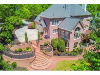 Expansive brick backyard featuring a landscaped terrace, manicured shrubs and lawn, and a multilevel deck at 2644 Nutwood Trce, Duluth, GA 30097
