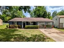 Charming single-story home featuring a well-manicured lawn, blue siding, and an inviting covered front porch at 5266 Long Green Ln, Stone Mountain, GA 30088