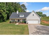 Charming home featuring a manicured lawn, covered porch, and a two-car garage at 104 Federal Path, Temple, GA 30179