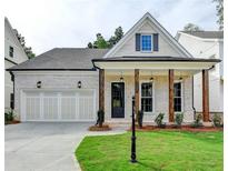 Charming home featuring a two-car garage, a welcoming front porch with wooden beams, and a well-manicured lawn at 2381 Siskin Square Rd, Duluth, GA 30096