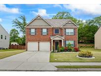 Inviting two-story brick home with a well-manicured lawn and a two-car garage at 3573 Stonebranch Ln, Loganville, GA 30052
