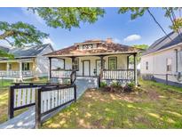 Charming white home with a cozy front porch and well-maintained lawn and attractive landscaping at 11 Poplar St, Porterdale, GA 30014
