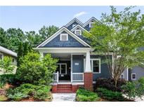 Charming two-story home with landscaped yard, brick steps, a porch swing, and stylish blue siding at 132 Olympic Pl, Decatur, GA 30030