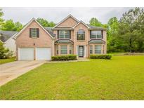 Charming two-story brick home featuring a well-manicured lawn, attached garage, and a welcoming front entrance at 4205 Post Oak Grv, Atlanta, GA 30349