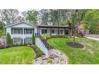 Beautiful exterior of home featuring manicured lawn, covered porch with wooden beams and landscaped walkway at 2668 Galahad Ne Dr, Atlanta, GA 30345