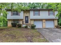 Split-level home with brick and siding, featuring an attached two-car garage and front yard at 5802 Oakleaf Dr, Stone Mountain, GA 30087