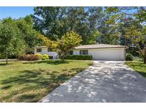 Charming one-story home featuring mature trees, a well-manicured lawn and a concrete driveway leading to an attached garage at 3331 Doyle Sw Ln, Marietta, GA 30060