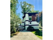 Unique contemporary house with white facade, rounded tower element, black trim, and private drive at 1215 Woods Ne Cir, Atlanta, GA 30324