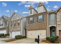 Charming townhome featuring a two-car garage and brick facade, complemented by manicured landscaping at 6595 Story Cir, Norcross, GA 30093