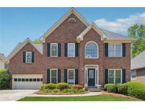 Charming brick home featuring a well-manicured lawn, black shutters, and an attached two-car garage at 1632 Chadwick Ridge Dr, Lawrenceville, GA 30043