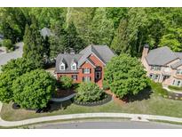 Beautiful two-story red brick home with a lush green lawn, manicured landscaping, and mature trees around the property at 3284 Bakers Mill Ct, Dacula, GA 30019