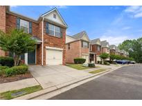 Charming brick townhome featuring an attached one-car garage and professionally landscaped surroundings at 5654 Lawley Dr, Alpharetta, GA 30022