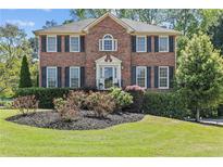 Beautiful brick home with manicured lawn, black shutters, and classic architectural details at 4257 Edgewater Nw Dr, Kennesaw, GA 30144