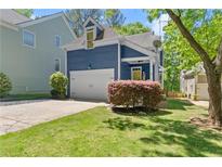 Blue two-story home featuring a one-car garage, a yellow front door, a manicured lawn, and mature landscaping at 2244 Spink Nw St, Atlanta, GA 30318