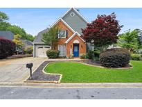 Charming brick and siding home featuring a well-manicured lawn and an inviting blue front door at 321 Hickory Sw Walk, Marietta, GA 30064