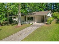 Charming single-story home with a covered carport, and lush green lawn surrounded by mature trees at 2740 Pasco Se Ln, Atlanta, GA 30316