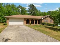 Charming brick ranch home featuring a two-car garage and a long driveway, surrounded by mature trees at 2944 Williams Pl, Snellville, GA 30078