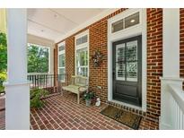 Charming brick porch featuring a bench, plants, and black front door with glass panels at 613 Brennan Dr, Decatur, GA 30033