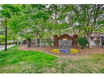 Welcoming entrance to The Woodlands at Webb Bridge community, featuring brick signage and colorful flowerbeds at 3107 Woodland Ln, Alpharetta, GA 30009