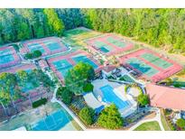 Aerial view of a community pool, tennis courts, and meticulously landscaped grounds with mature trees at 1336 Amberwood Dr, Woodstock, GA 30189