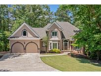 Charming two-story home featuring a well-manicured lawn, arched windows, and an attached two-car garage at 1336 Amberwood Dr, Woodstock, GA 30189