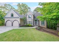 Charming home featuring a manicured lawn, arched garage doors, and mature trees surrounding the property at 1336 Amberwood Dr, Woodstock, GA 30189