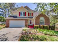 Charming two-story home with red accents, a well-manicured lawn, and a two-car garage at 3095 Willow Park Dr, Dacula, GA 30019