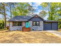 Charming bungalow featuring a brick exterior, dark roof, and a vibrant teal front door at 1554 Cardinal Rd, Jonesboro, GA 30238