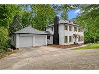 Charming two-story home with white siding, dark shutters, a black chimney and a two-car garage at 6659 Manoleta Dr, Lithonia, GA 30038