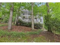 Two-story home featuring dual balconies, surrounded by mature trees and lush greenery at 3876 Winners Ct, Marietta, GA 30062