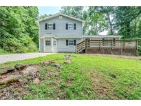 Charming two-story home with a wooden deck, gray siding, black shutters, and mature trees at 270 Hunt Ridge Dr, Stockbridge, GA 30281