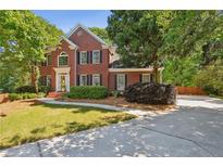 Beautiful two-story brick home with a well-manicured lawn and mature trees, creating a welcoming curb appeal at 5100 Sunset Maple Trl, Lilburn, GA 30047